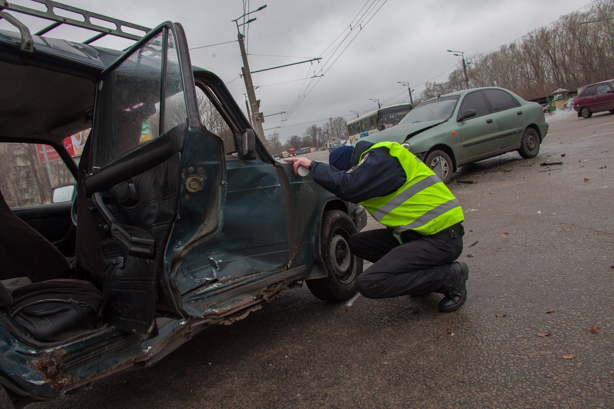 Полицейский осматривает поврежденный автомобиль