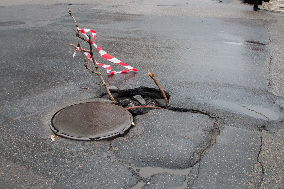 Яму временно обозначили ветками и лентами.