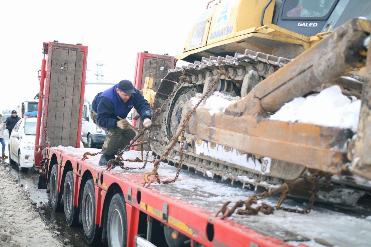Водитель пытается закрепить бульдозер, чтобы он не упал