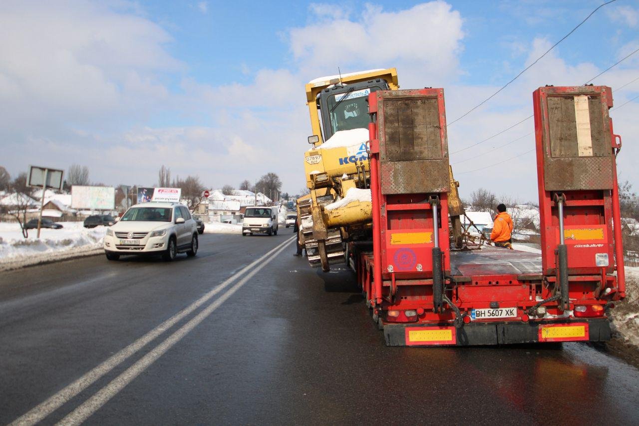Проезжающие автомобили нисколько не смущает накренившийся бульдозер