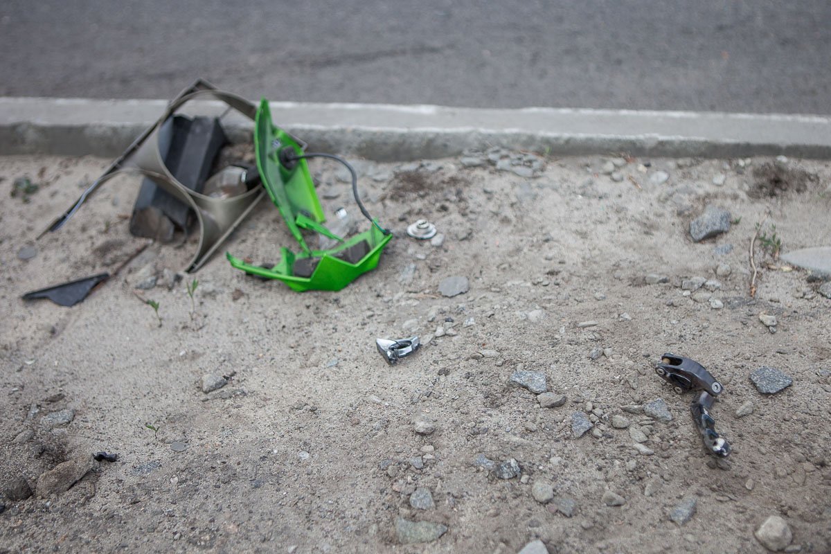 Осколки мотоцикла рассыпаны по дороге и тротуару