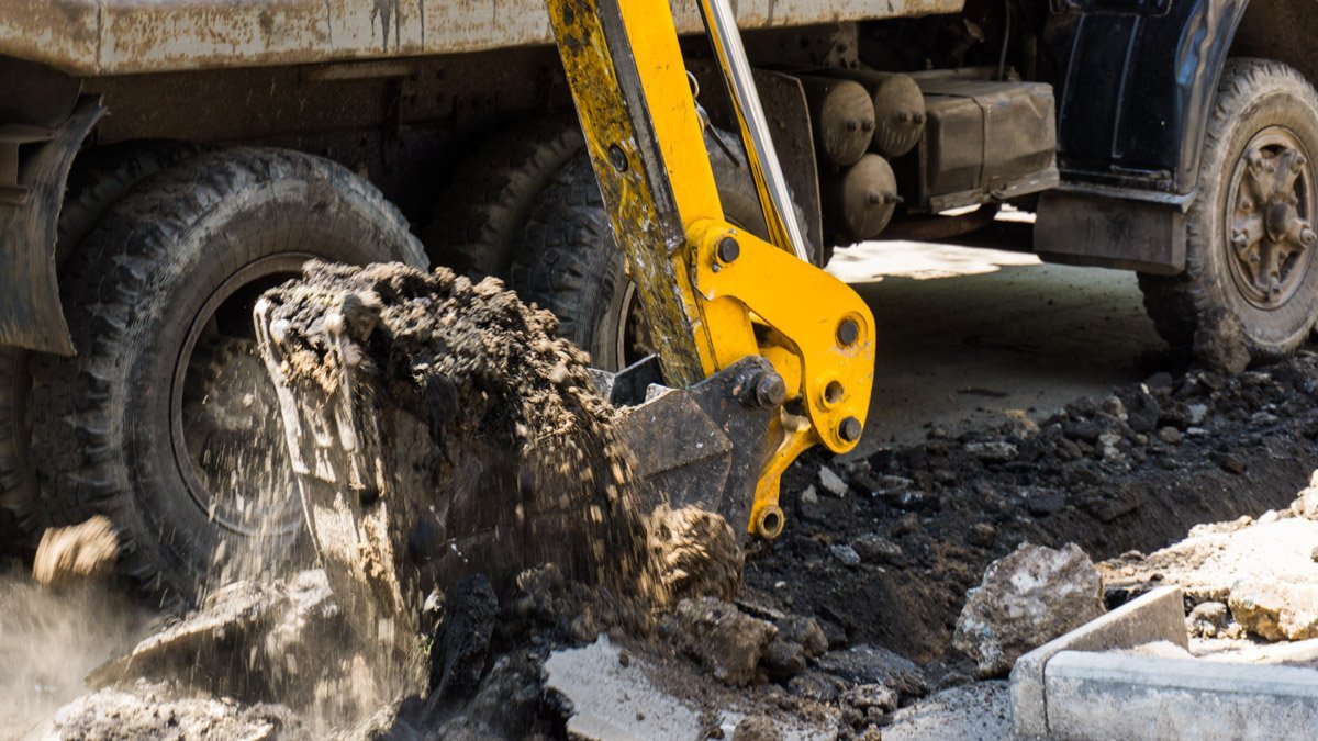 Коммунальщики роют траншею для установки бордюрного камня Коммунальщики роют траншею для установки бордюрного камня