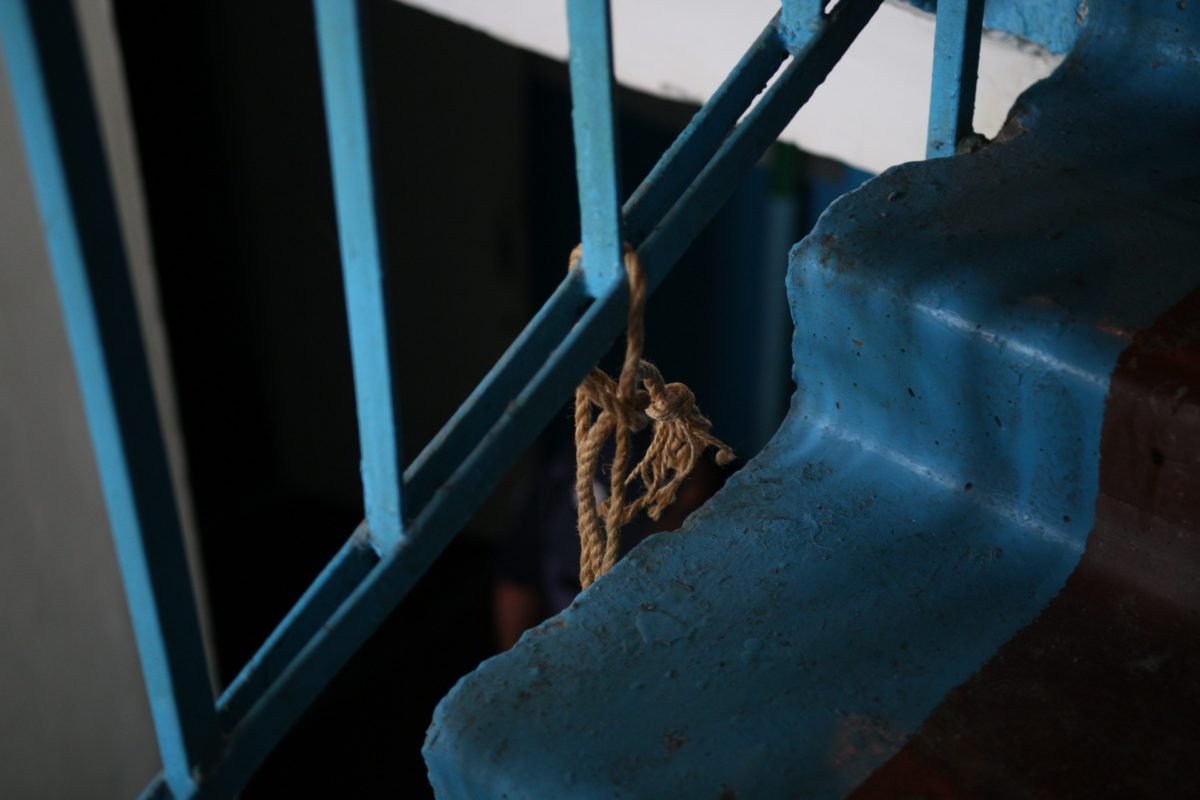 Мужчина привязал веревку к перилам лестницы Мужчина привязал веревку к перилам лестницы