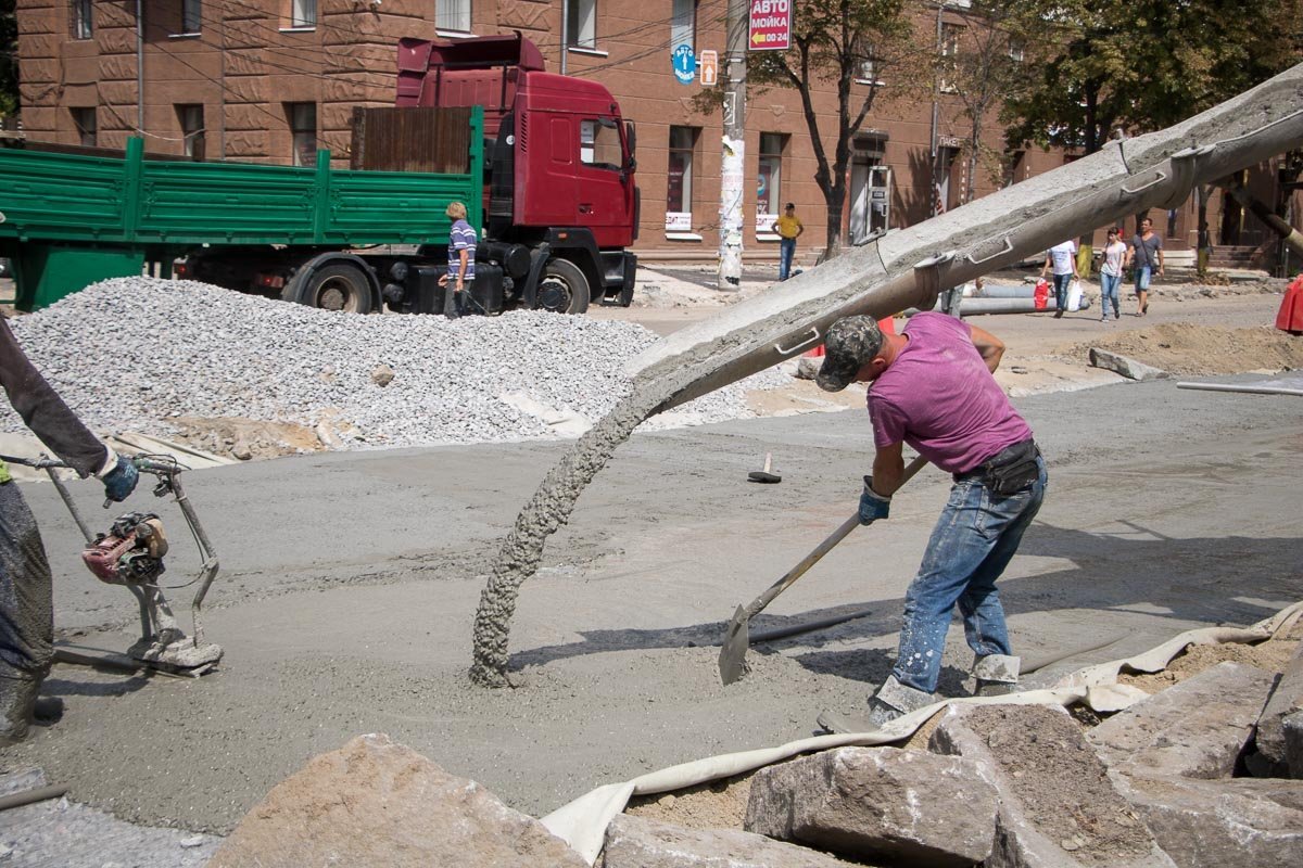 Рабочие лопатами разглаживают бетон