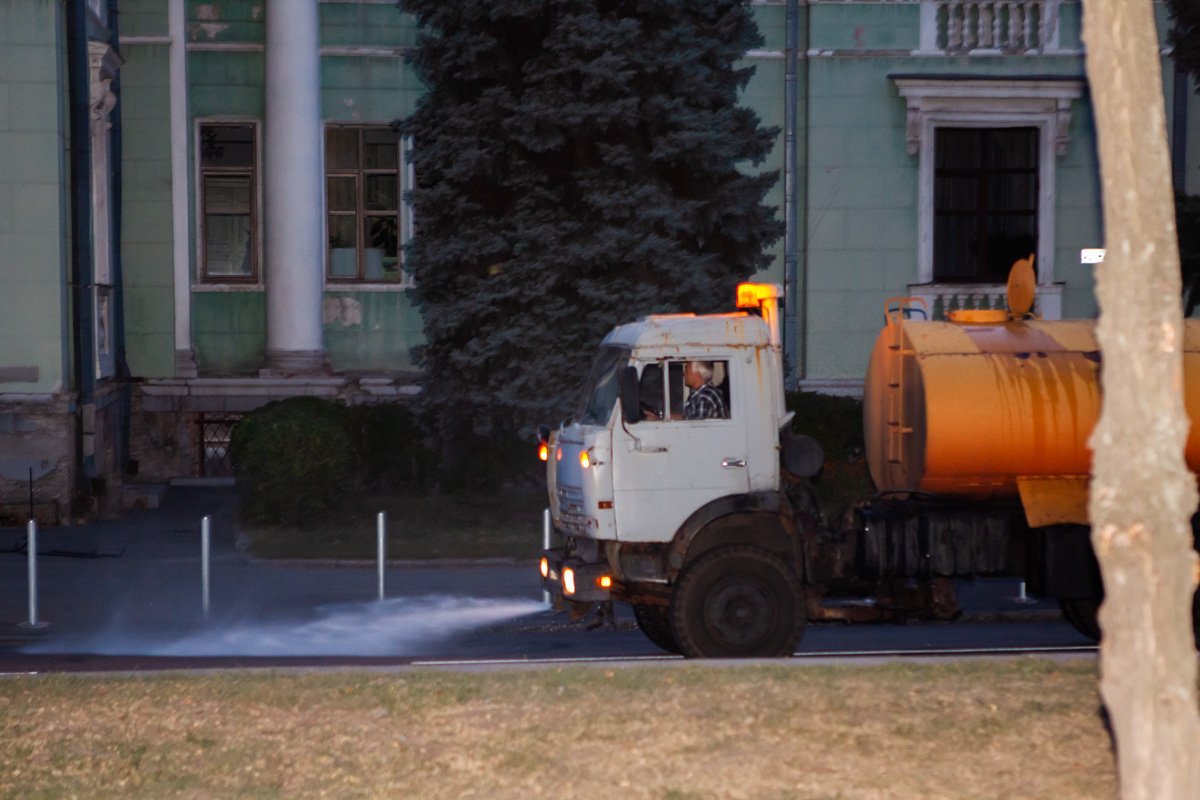 Поливальные машины моют дорогу водой Поливальные машины моют дорогу водой