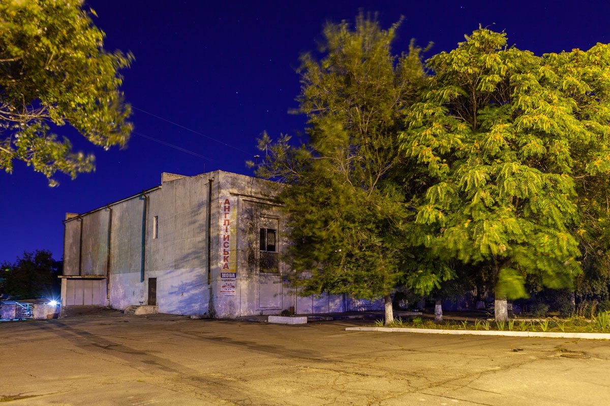 Старые серые здания прячутся за деревья