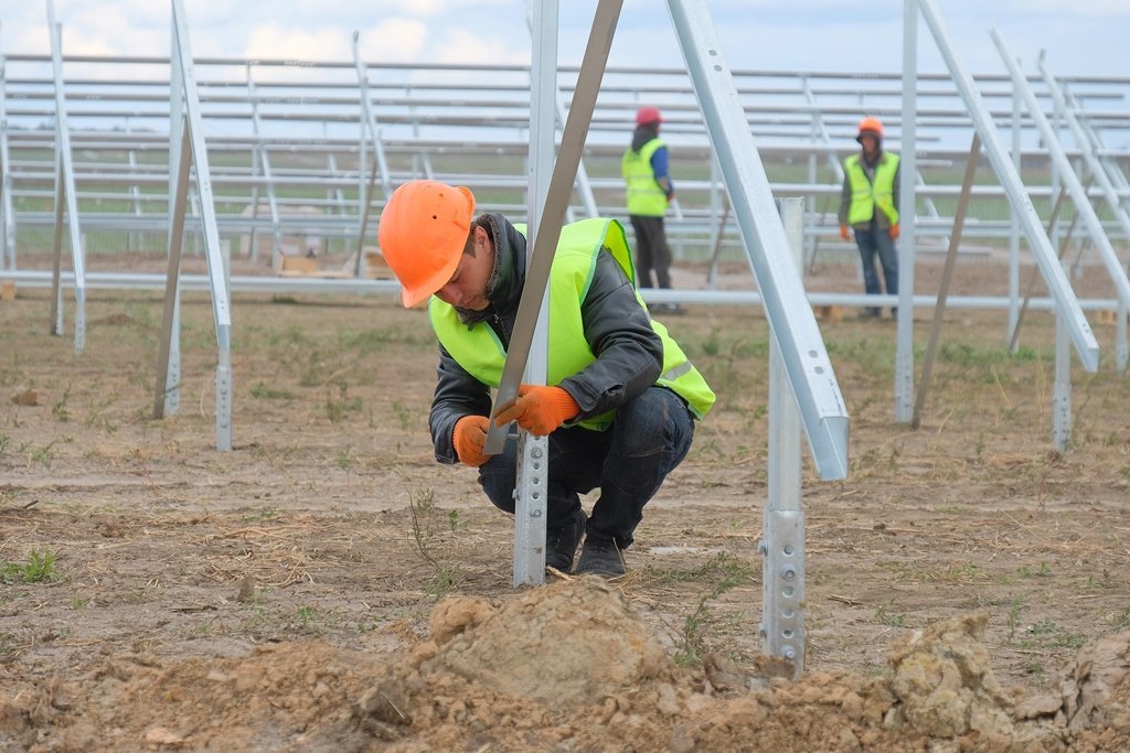 Рабочие монтируют основания для панелей Рабочие монтируют основания для панелей