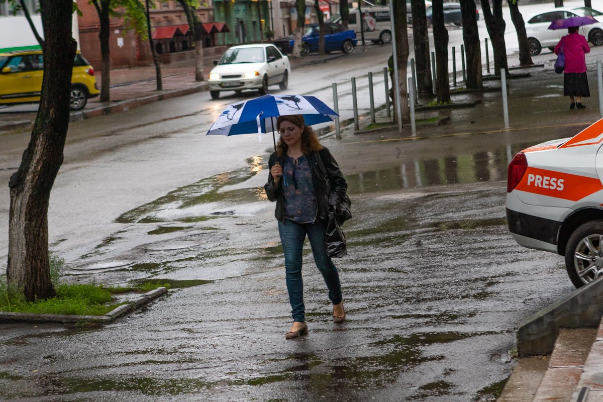 Вооружившись зонтами, жители следуют по своим делам Вооружившись зонтами, жители следуют по своим делам