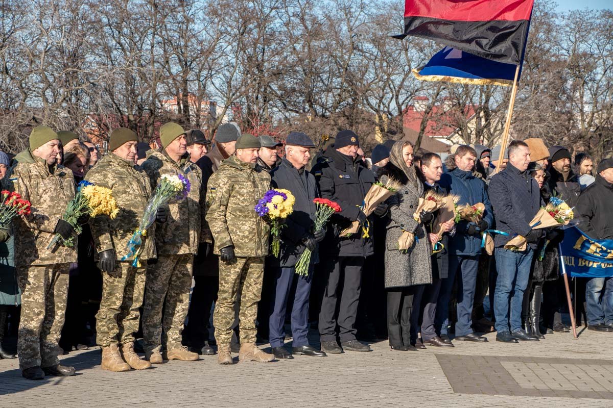 В руках у присутствующих - цветы, окрашенные в желтые и голубые цвета, и колосья В руках у присутствующих - цветы, окрашенные в желтые и голубые цвета, и колосья