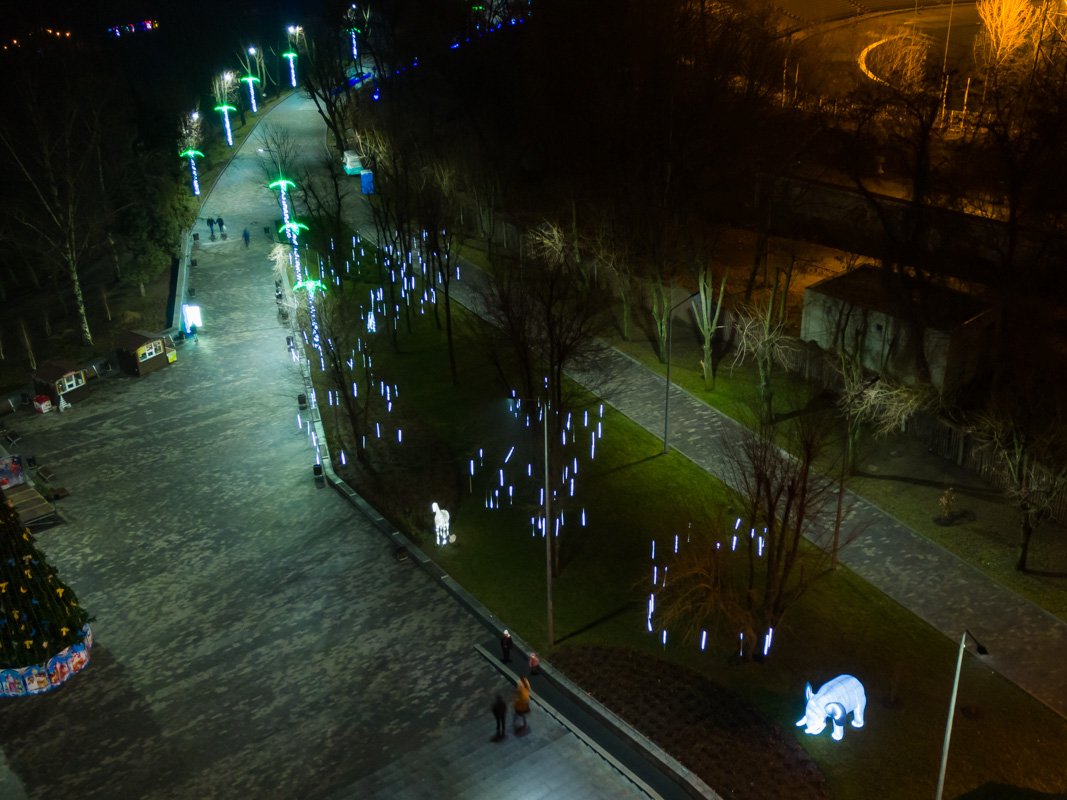 Многие люди гуляют в парке, несмотря на позднее время 