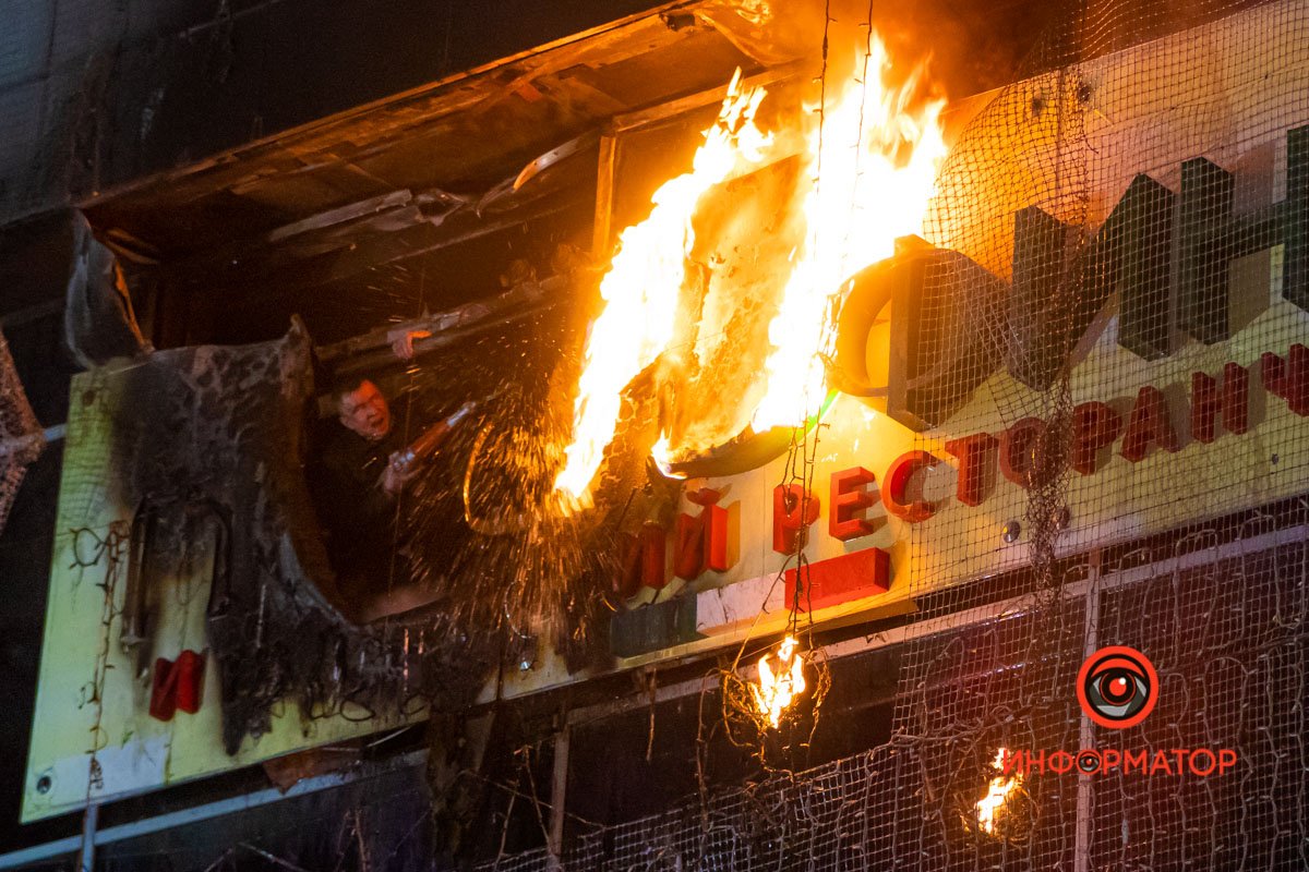 Сотрудник ТЦ пытается потушить вывеску 