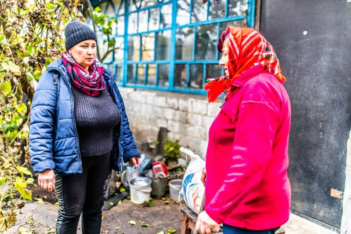 Жінка допомагає літнім людям