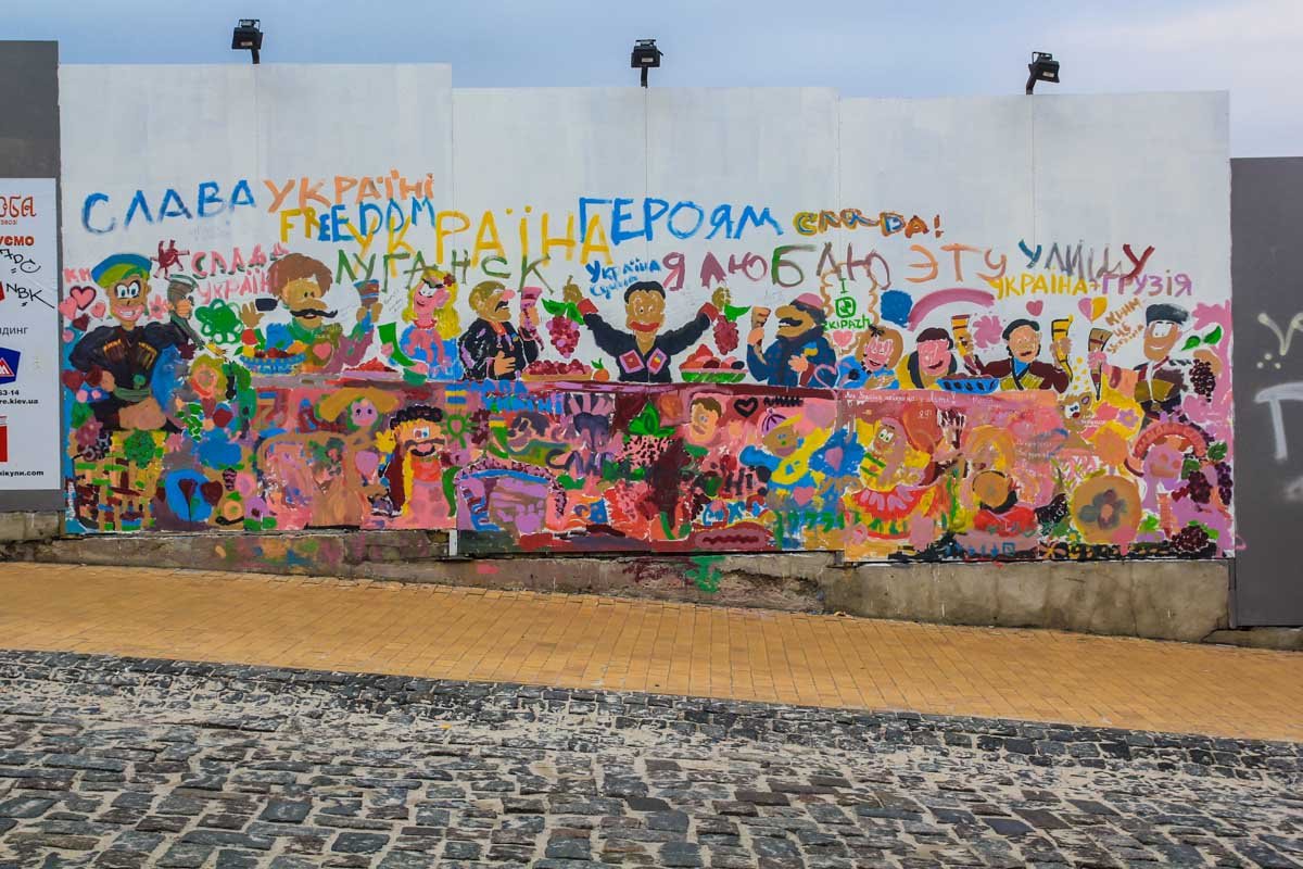 Лубочное грузино-украинское застолье украшает строительный забор на Андреевском спуске