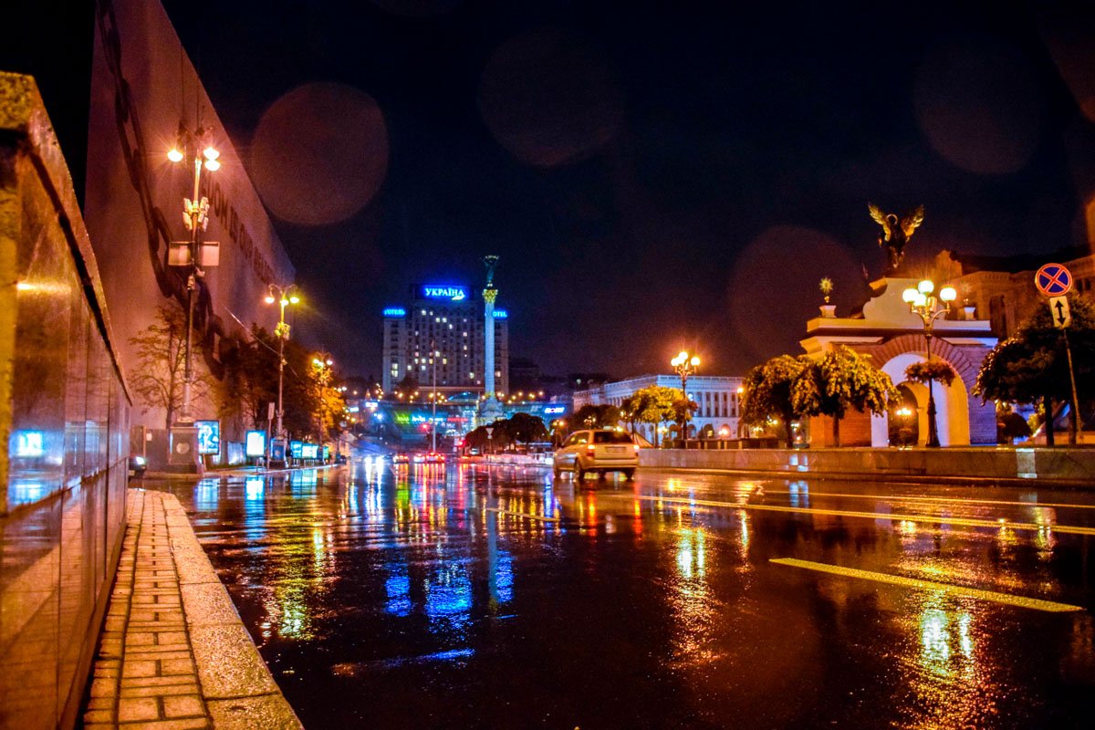 Огни ночного города отражаются в мокром асфальте