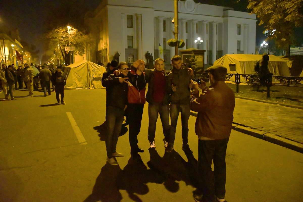 Прохожие делают фото на фоне палаточного городка