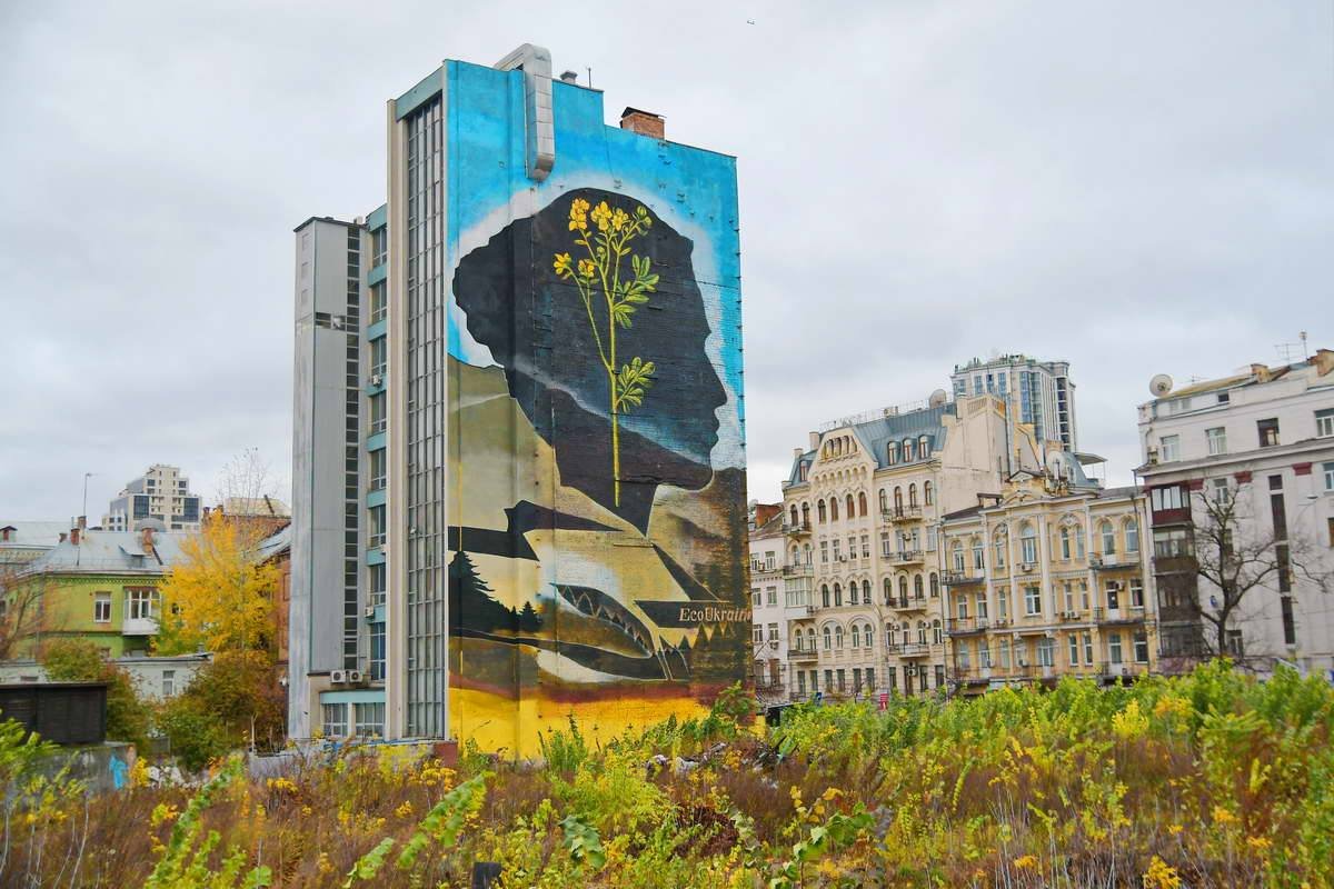 На фасаде здания прохожие видят черный женский профиль с большим желтым цветком внутри