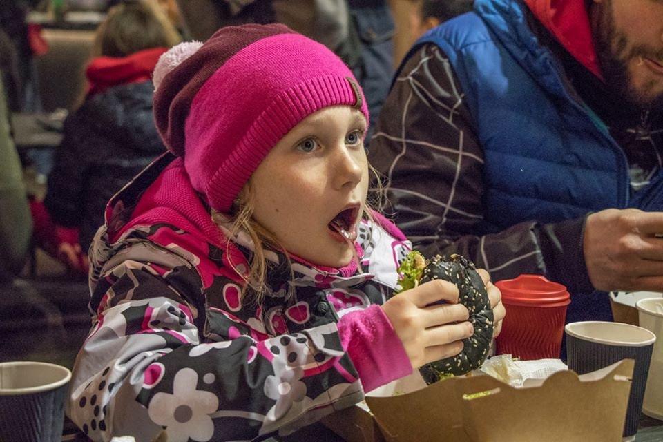 Девочка наслаждается бургером Девочка наслаждается бургером