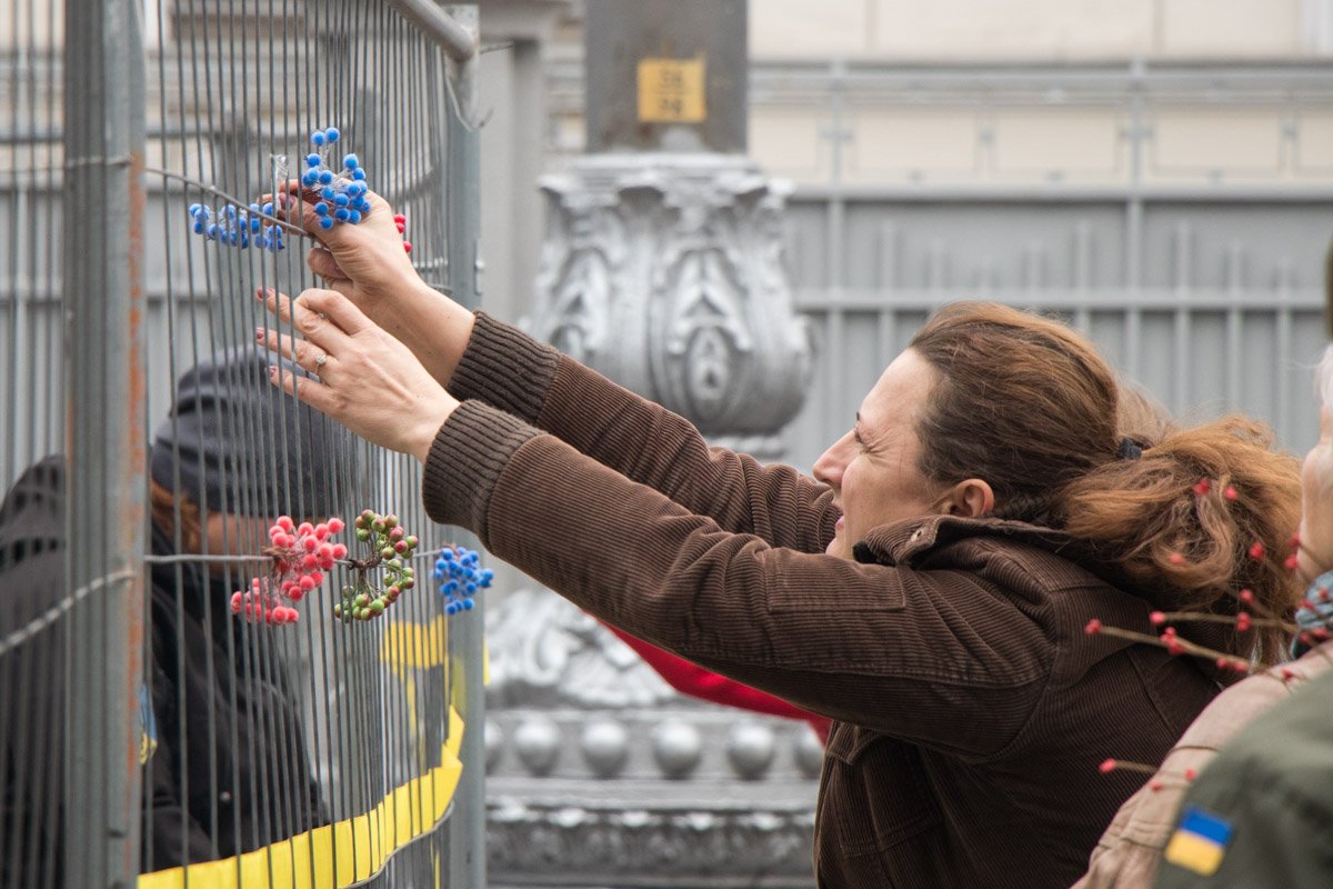 Женщина украшает ограду палаточного городка под Радой