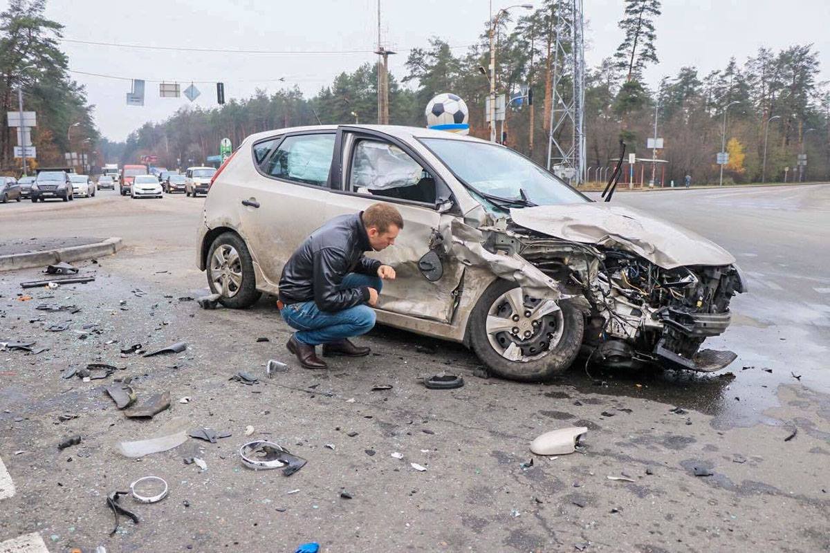 Владелец автомобиля осматривает повреждения Владелец автомобиля осматривает повреждения