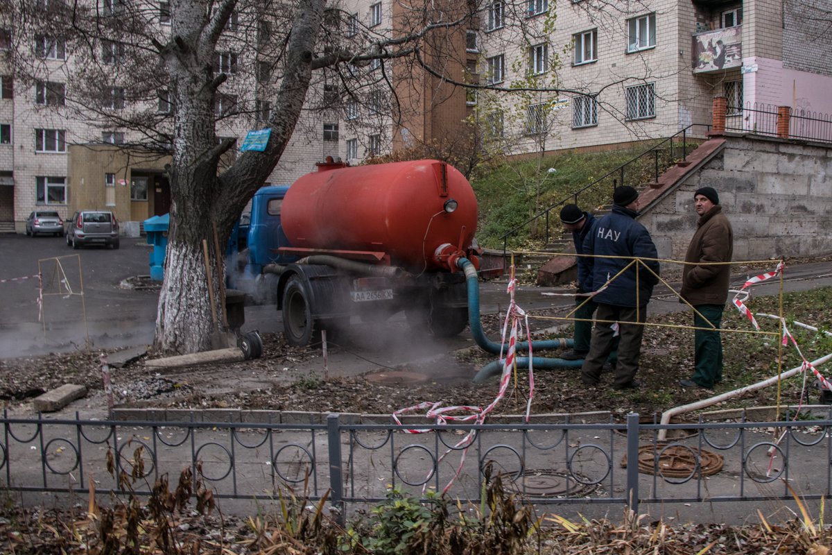 Они откачивают воду с канализационного люка, чтобы устранить повреждение трубы Они откачивают воду с канализационного люка, чтобы устранить повреждение трубы