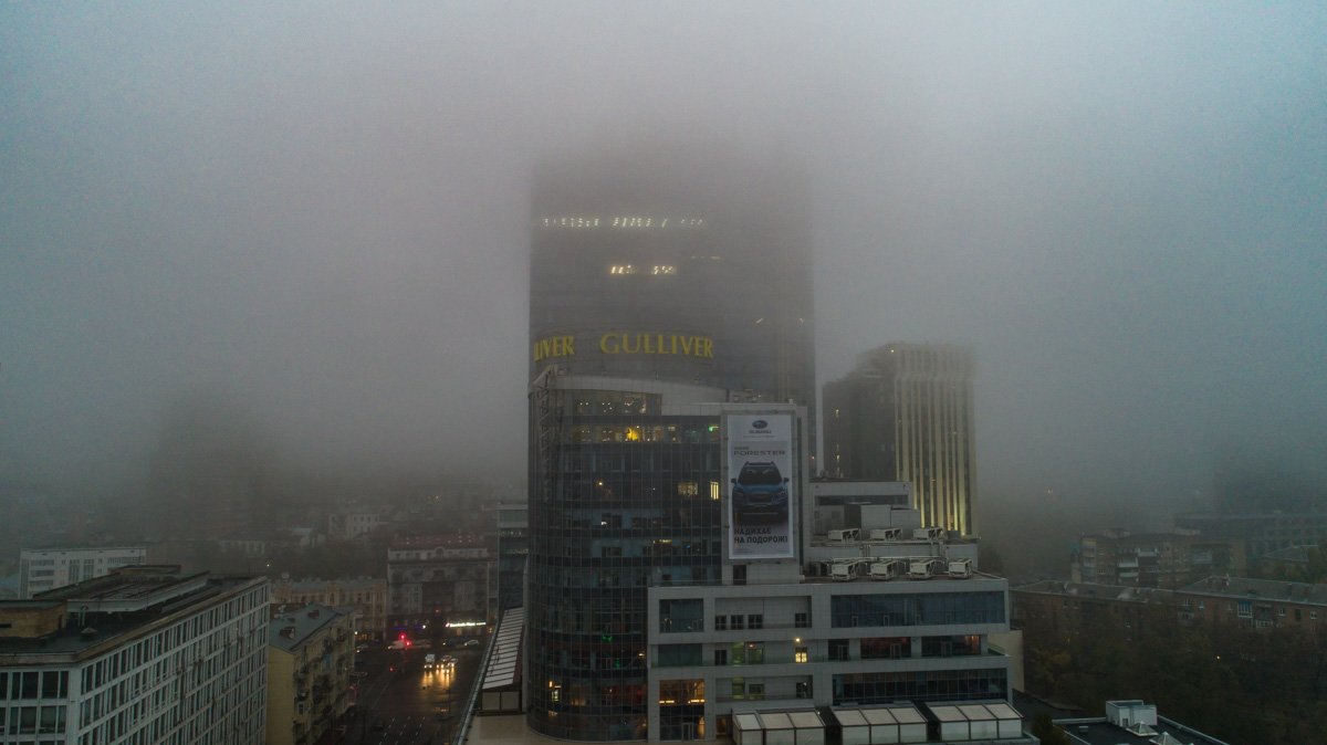 Верхушки домов едва виднеются сквозь густое белое полотно из тумана Верхушки домов едва виднеются сквозь густое белое полотно из тумана