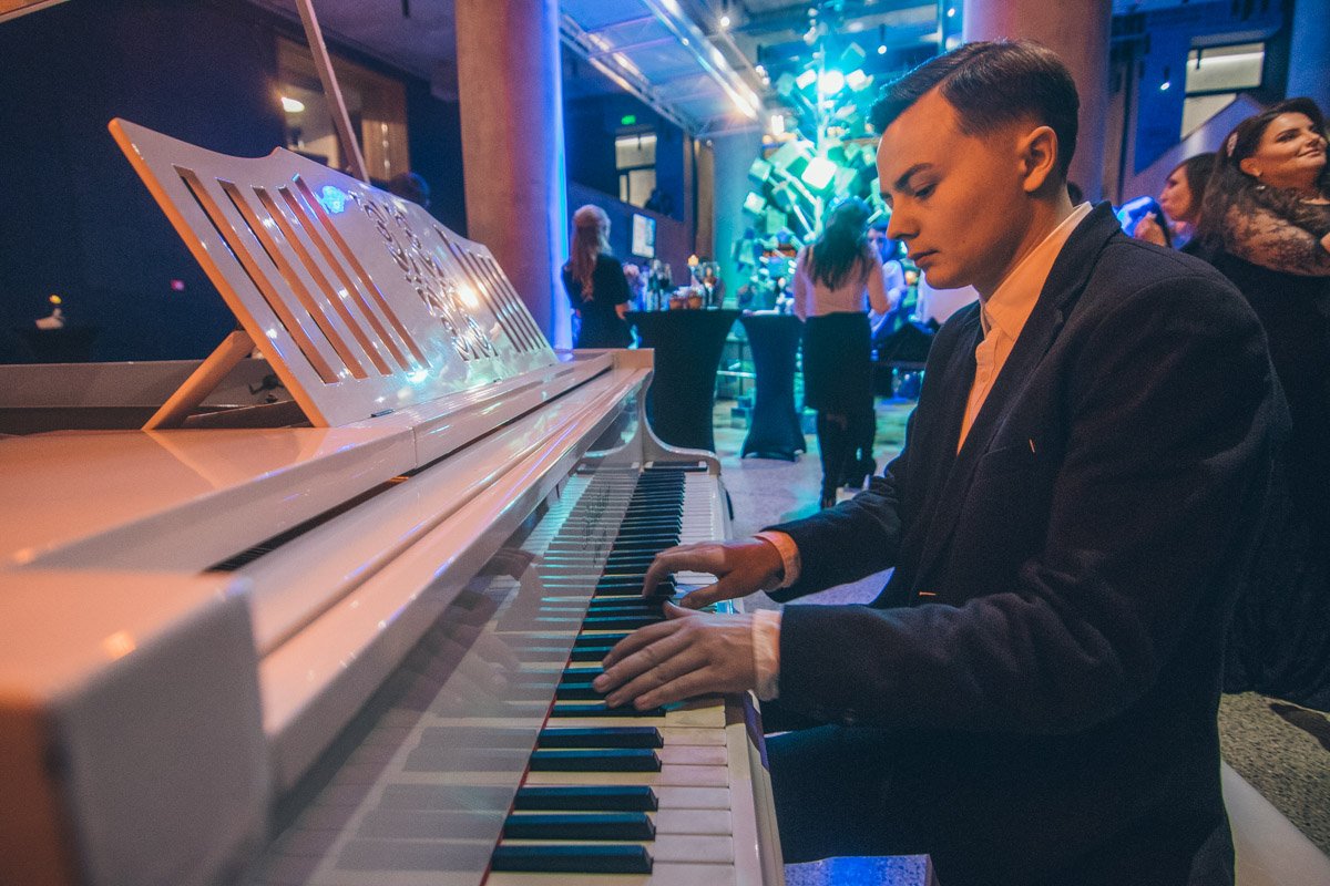 За белым роялем пианист играл живую музыку За белым роялем пианист играл живую музыку