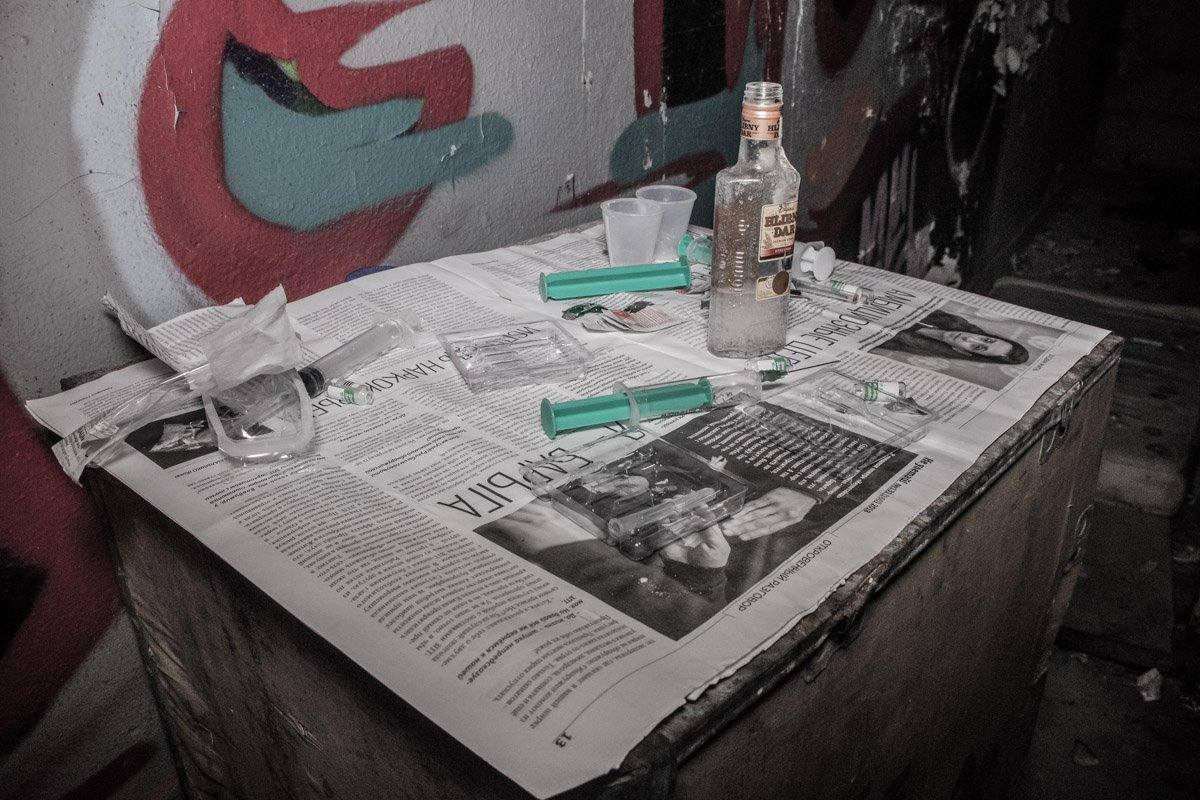 Недалеко от трупа стояла бутылка алкогольного напитка и две рюмки, а также несколько шприцов и пустых ампул Недалеко от трупа стояла бутылка алкогольного напитка и две рюмки, а также несколько шприцов и пустых ампул