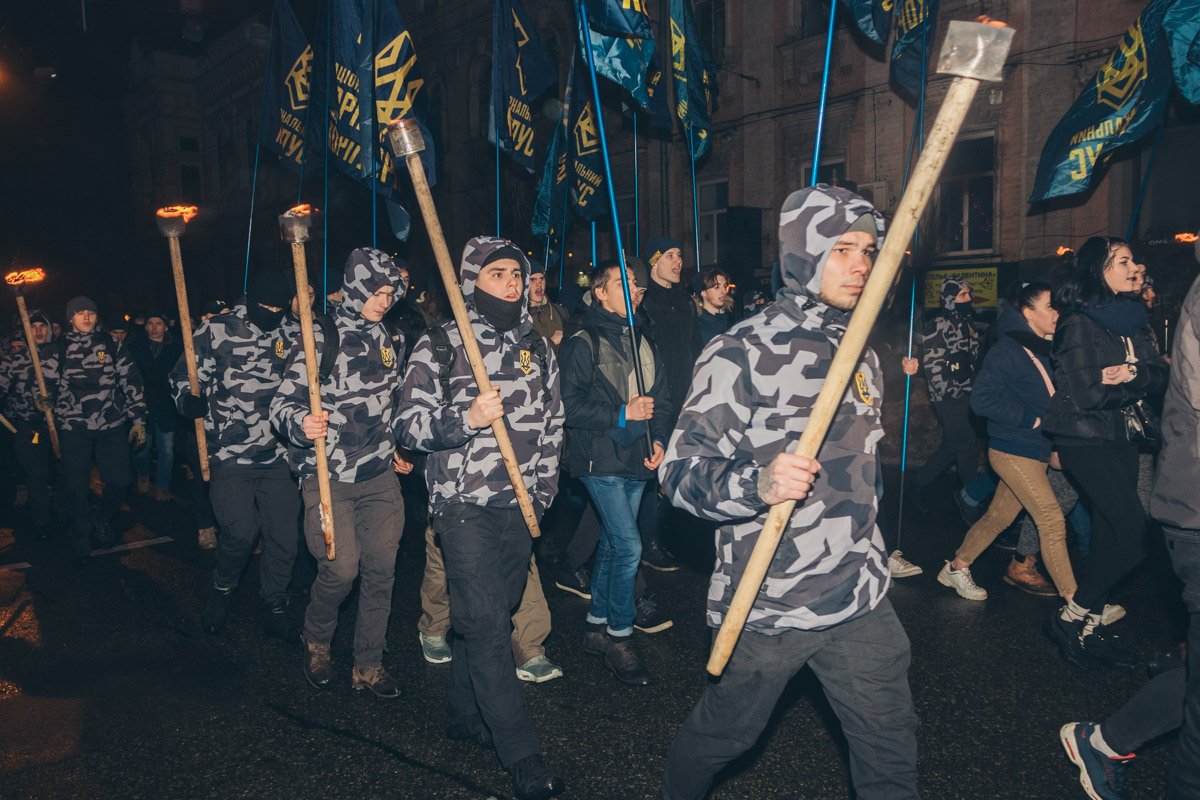 Люди идут с факелами и украинскими флагами в руках Люди идут с факелами и украинскими флагами в руках
