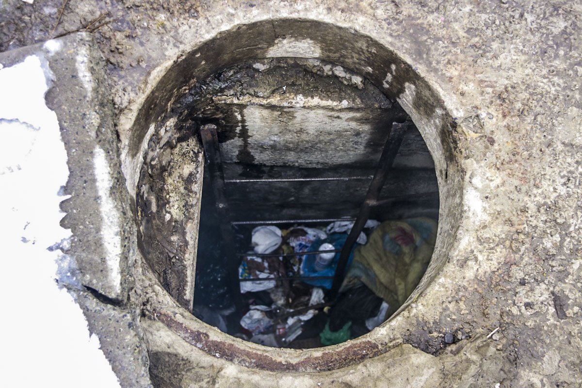 В канализации обустроено спальное место с одеялами и подушками, много посуды, продукты и бутылки из-под алкоголя