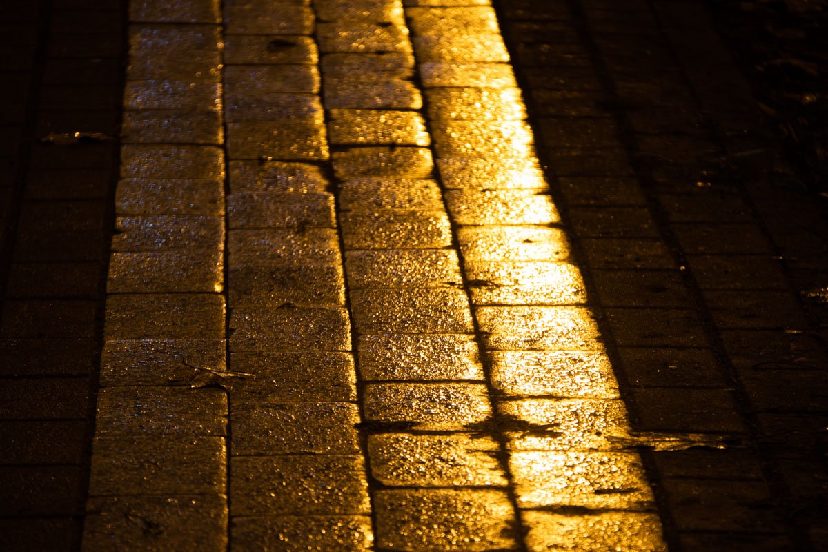 Мокрая плитка отражает свет ночных фонарей