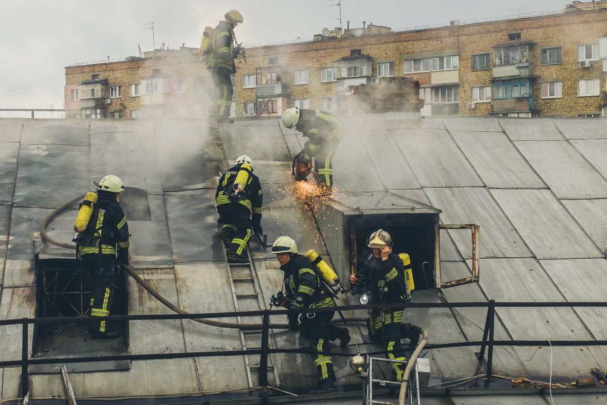 На чердак дома проход закрыт, это усложняет работу спасателей, с помощью бензореза они снимают с крыши листы профнастила, чтобы попасть внутрь
