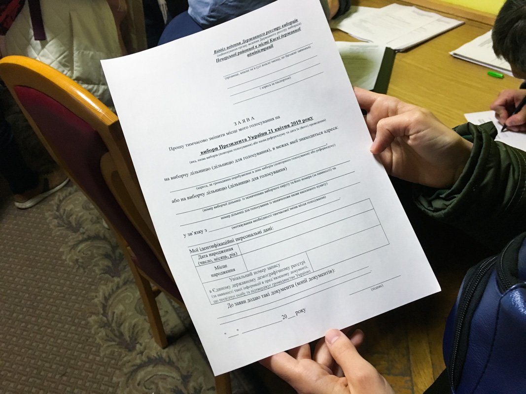 В коридоре, где находится очередь, разложили стопки бланков заявлений, чтобы их заполнили заранее