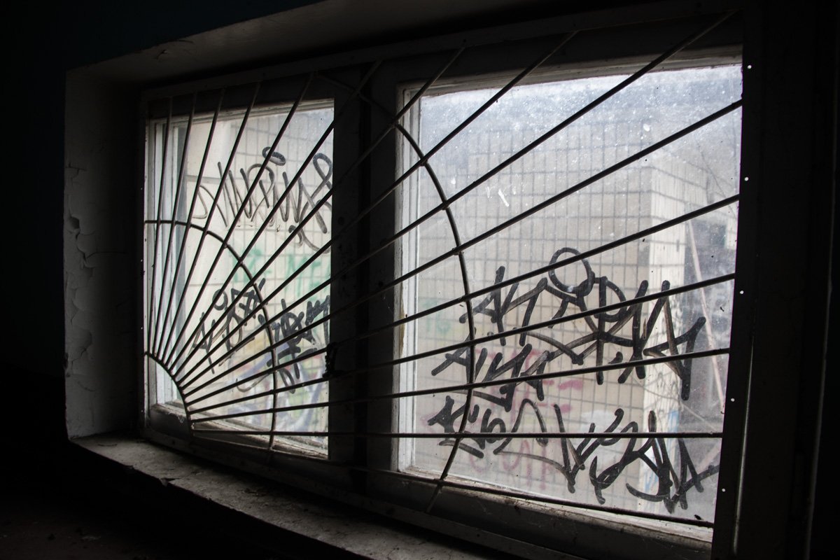 Окна и стены здания исписали уличными граффити 