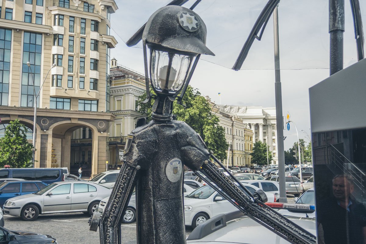 Фонарь-полицейский держит в руках зонт, который должен защищать жителей от непогоды Фонарь-полицейский держит в руках зонт, который должен защищать жителей от непогоды