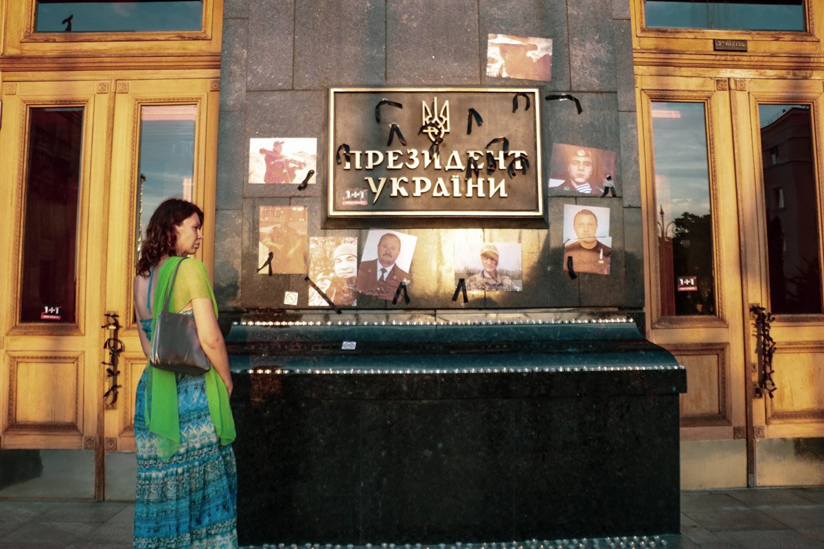 Люди наклеили на стену Администрации Президента фотографии бойцов, которые погибли в зоне ООС в последние недели