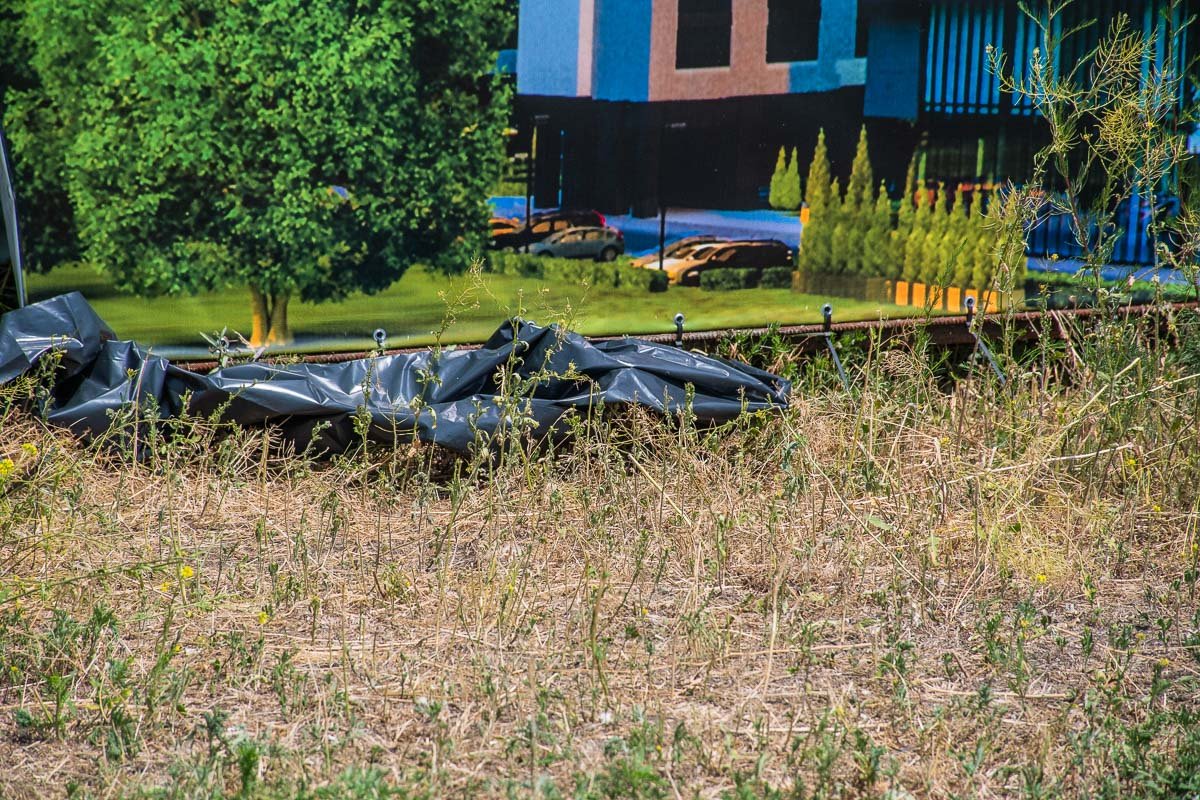 Тело лежало между забором и рекламным баннером Тело лежало между забором и рекламным баннером