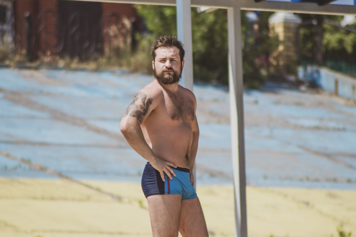 Серьезные лица пляжников связанны со втянутым животом 