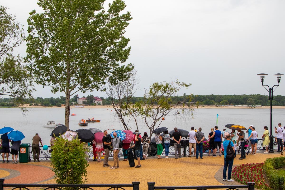 В парке пошел дождь, поэтому люди спрятались под зонты и навесы