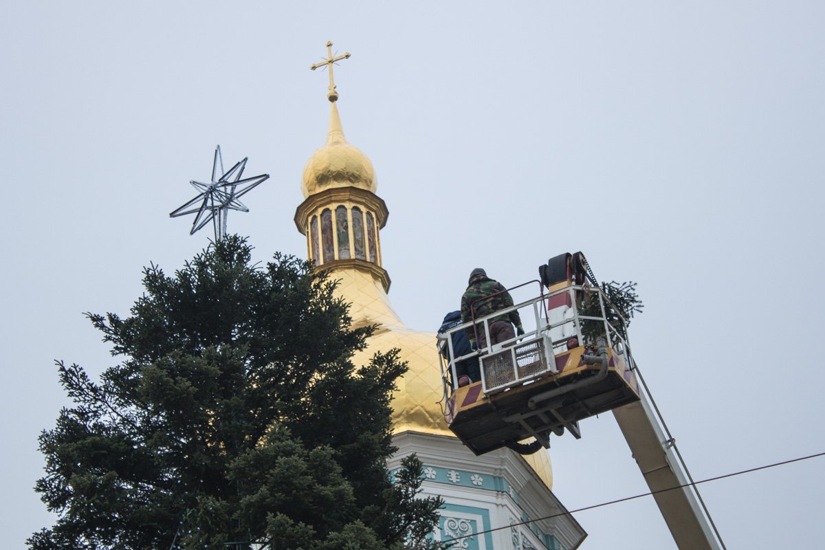 Дерево украшают при помощи подъемных кранов