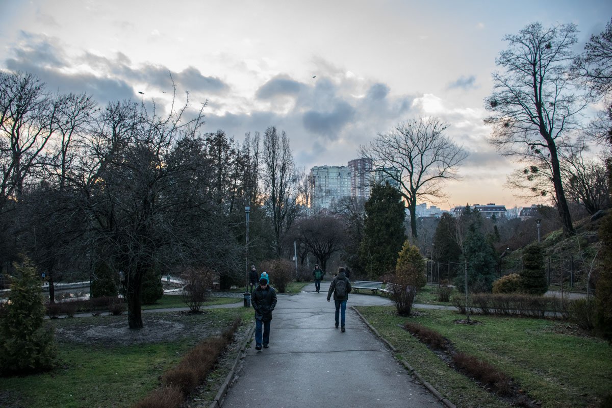 Смотря под ноги, идут по парку прохожие