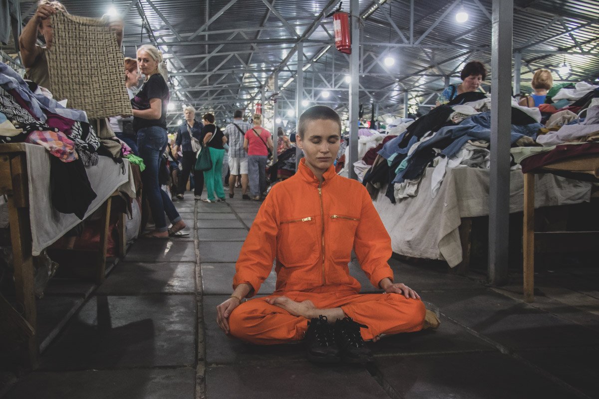 На улицах города медитирует девушка в оранжевом костюме