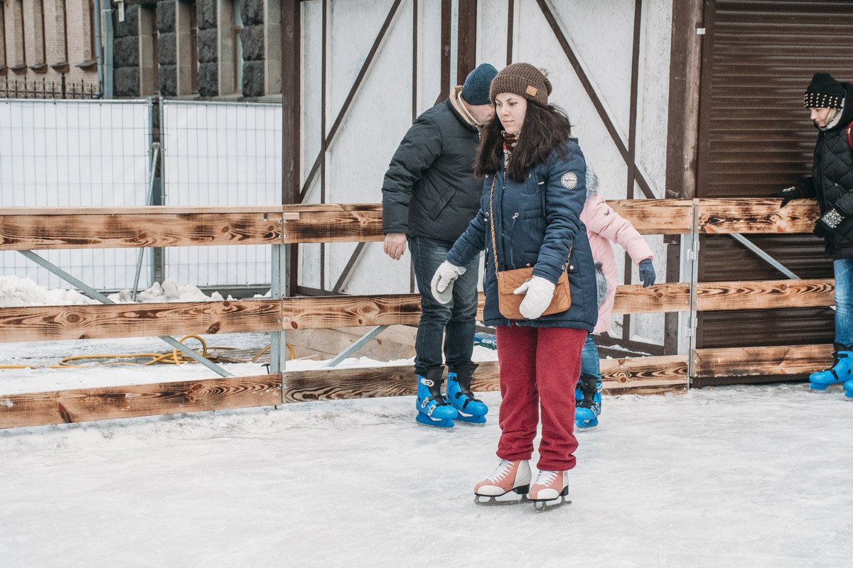 Люди катаются на катке в праздник Рождества Люди катаются на катке в праздник Рождества