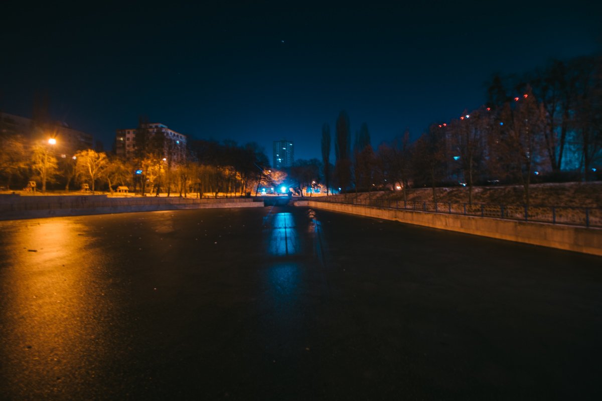 Гладкое зеркало льда на поверхности озера отражает ночные огни парка