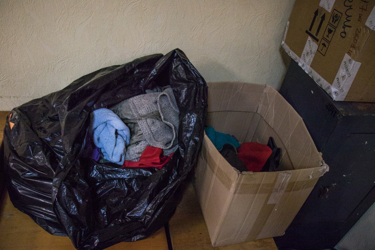 Одежда для бездомных здесь разложена в коробке и мусорном пакете