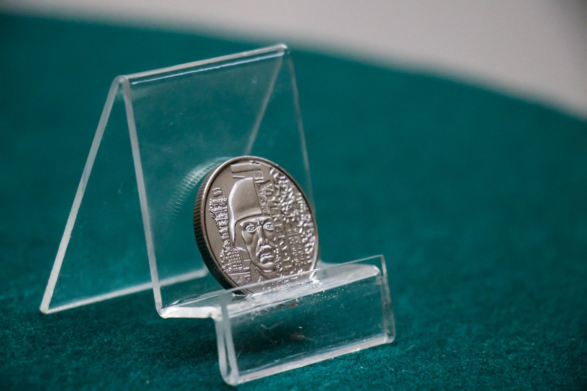 На реверсе за спиной воина полуразрушенная диспетчерская башня с украинским флагом