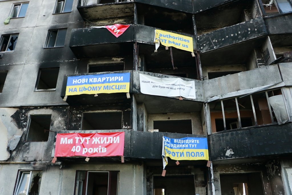 На зруйнованих будинках банери від власників квартир, які просять відбудувати іхне житло саме тут