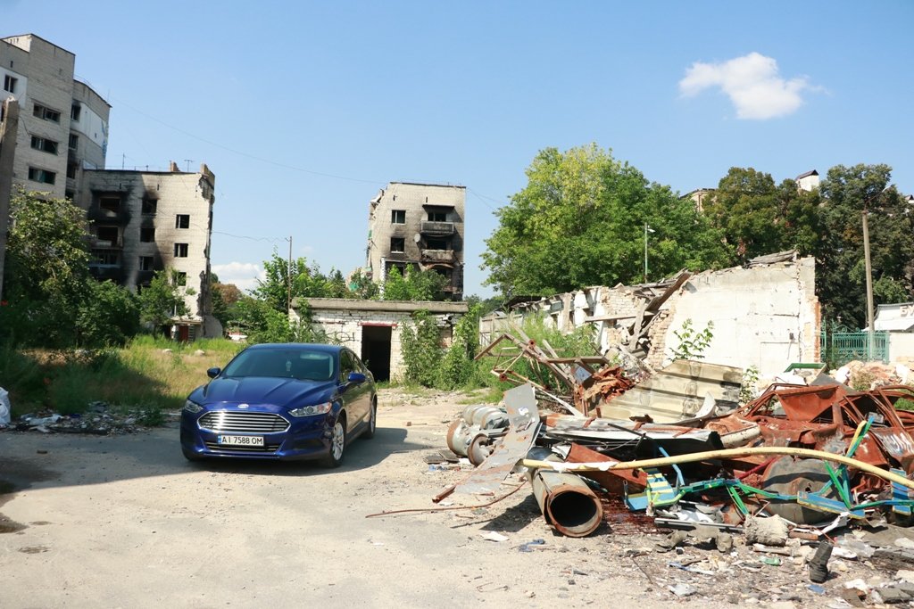 Біля знищених багатоповерхівок де-не-де стоять автівки власників, що намагаються там жити далі чи наводити порядки, відбудовувати житло