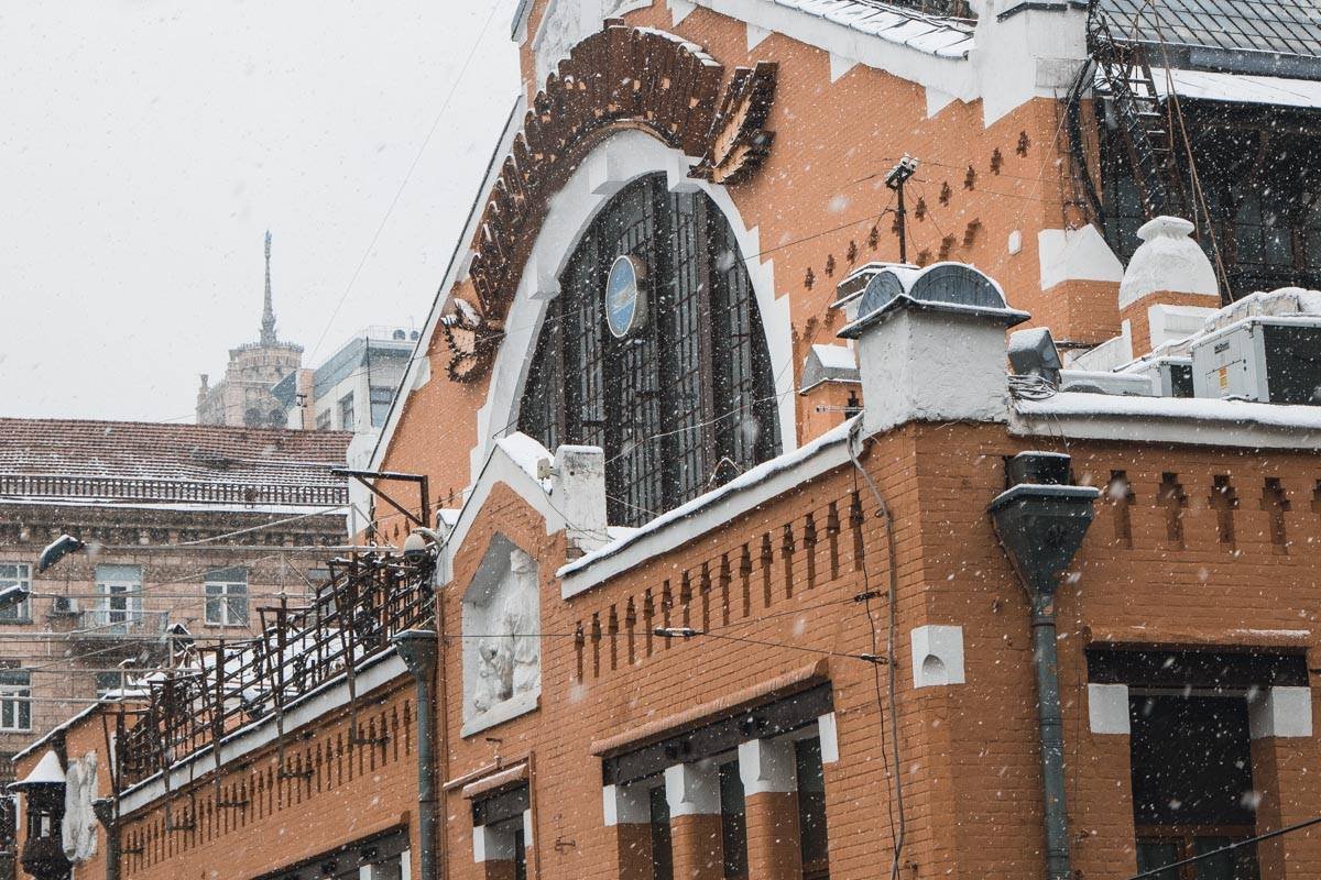 Снежинки неспешно кружатся и опускаются на здания, покрывая его снежным покрывалом