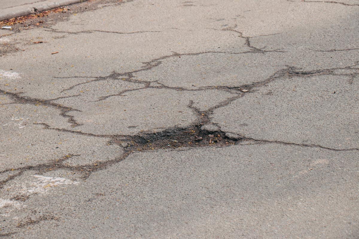 На асфальте видны ямы и трещины