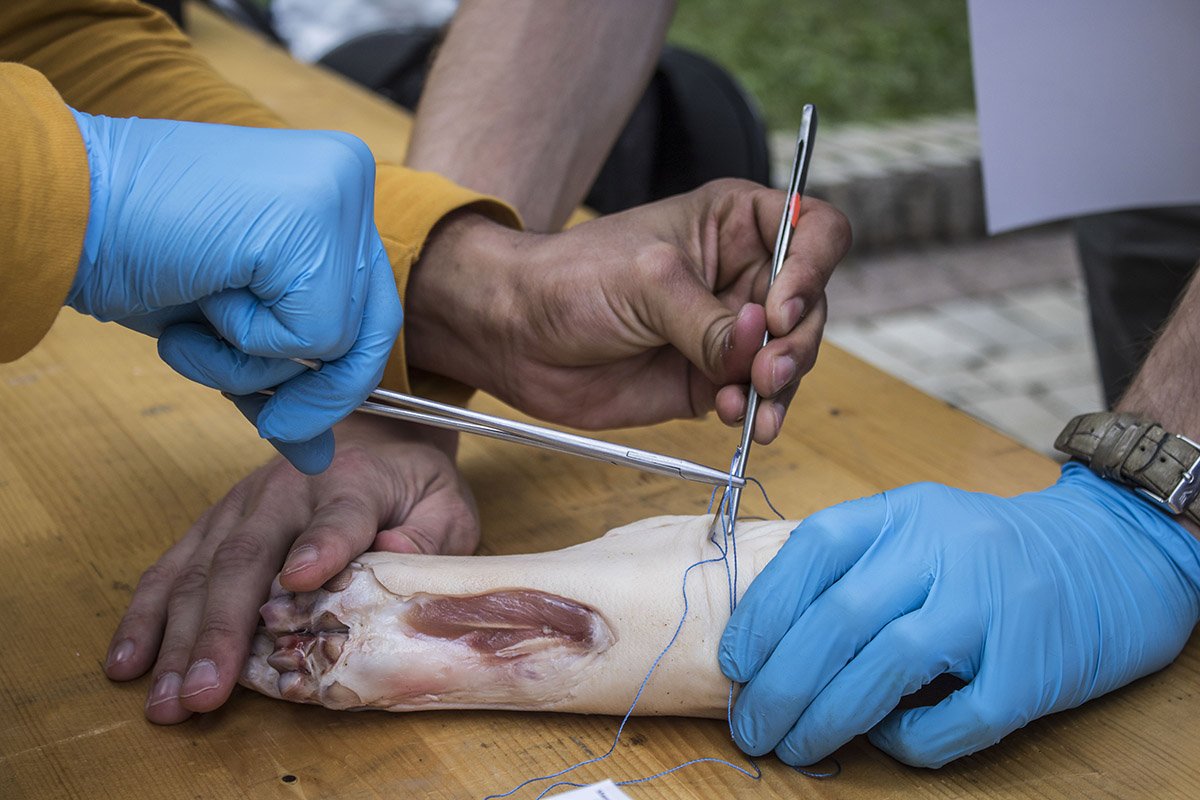 Один из стендов показывает разные виды хирургических швов, зашивая бананы, поролоновые губки и свиные ноги